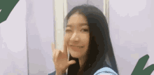 a woman with long black hair is making a peace sign with her finger .