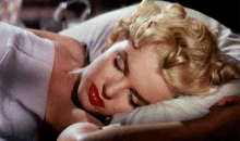 a woman with red lipstick is sleeping on a bed
