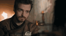 a man with a beard is wearing a brown leather jacket with a badge on it that says ' a ' on it