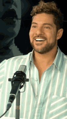 a man in a blue and white striped shirt stands in front of a microphone