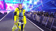 a woman in a yellow and black outfit is walking down a runway in front of a crowd .