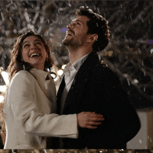 a man and a woman are hugging and laughing in the rain