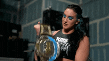 a woman in a kris top holds a wrestling belt