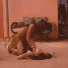 two women are fighting on the floor in front of a couch