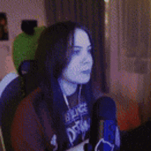 a girl with green hair is sitting in front of a microphone in a room .