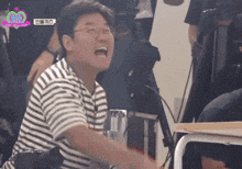 a man wearing glasses and a striped shirt is laughing in front of a camera with a pink heart on it