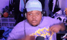 a man wearing headphones and a blue hat is sitting in front of a microphone .