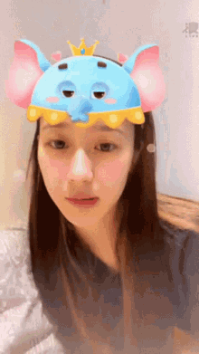 a woman wearing a blue elephant headband with a crown on top
