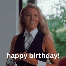 a woman in a black vest and white shirt is smiling and saying happy birthday