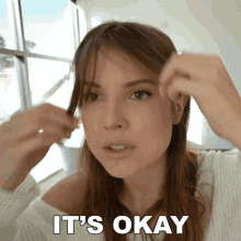 a woman is holding her hair and the words it 's okay are above her head