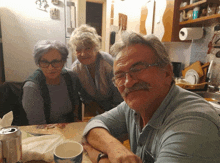 a man with glasses and a mustache sits with two women