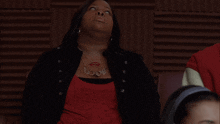 a woman wearing a red shirt and a necklace has a tattoo on her chest that says ' i love you '