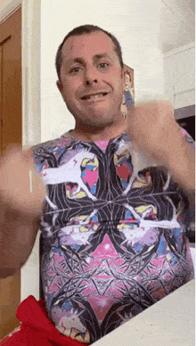 a man wearing a colorful shirt is giving a thumbs up sign .