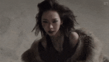 a woman is wearing a fur coat and a necklace
