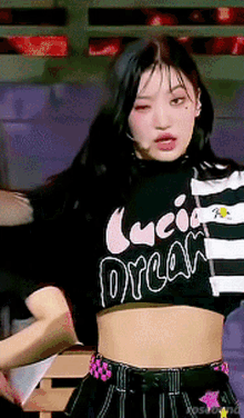 a girl is wearing a black and white striped crop top with the word dream on it .