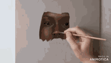 a person is painting a face with a brush and the words made in animatica are visible