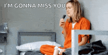 a woman in a jail cell is sitting on a bed holding a cell phone and crying .