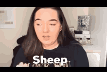 a woman is making a funny face while wearing a black shirt that says `` sheep '' .