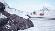 a car is driving down a snowy road in front of a red building