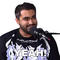 a man wearing a shirt that says yeah is talking into a microphone