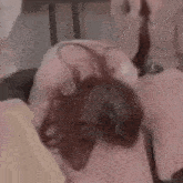 two women are sitting next to each other on a couch . one of the women is covering her face with her hands .