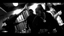 a black and white photo of a group of people dancing with a white cup in the foreground .
