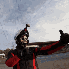 a man wearing a helmet with a skull mask on his face gives a thumbs up