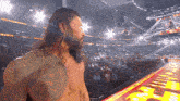 a man with long hair and a tattoo on his chest stands in front of a crowd in a stadium