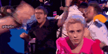 a man in a pink shirt is surrounded by other people with the hashtag gigigx on the bottom right