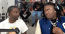 two men are sitting next to each other in front of a microphone in a room .