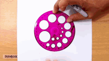 a person is drawing circles on a piece of paper with a pen that says drawbook