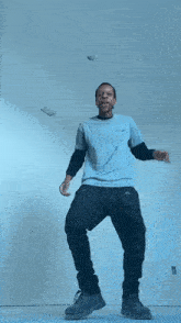 a man in a blue shirt and black pants is jumping in the air and laughing .
