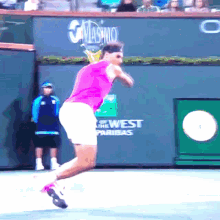 a tennis player is jumping in the air in front of a wall that says west paridas