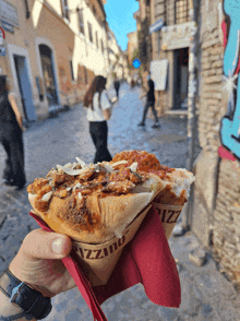 a person holding a pizza in a cone that says pizzino