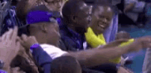 a group of people are sitting in a stadium holding hands and laughing .