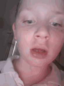 a close up of a baby 's face with a white shirt