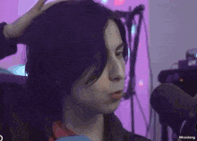a woman with long black hair is making a funny face while talking into a microphone .