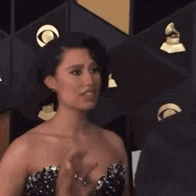 a woman in a strapless dress is smiling at the camera while standing on a red carpet .