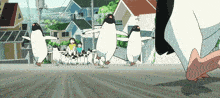 a group of penguins are walking down a street in front of a building that has the word kiwi on it