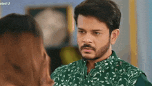 a man with a beard and a green shirt is looking at a woman