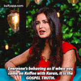 a woman in a red dress is sitting on a blue couch talking to a man .
