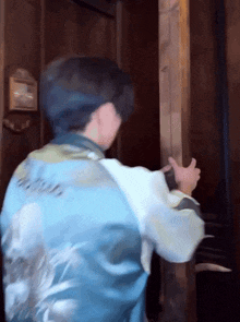 a man in a blue jacket is standing in front of a wooden wall .