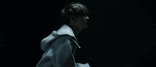 a person in a white hoodie is walking in the dark .