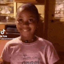 a little girl in a pink shirt is smiling and looking at the camera .