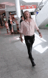 a man in a pink shirt is walking in a store