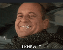 a man with a scarf around his neck smiles and says " i knew it "