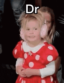 a little girl in a minnie mouse costume is being held by a woman in a red dress .
