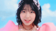 a young girl wearing a pink dress and a headband is smiling