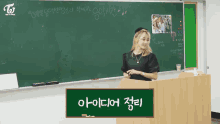 a woman stands at a podium in front of a blackboard with twice on it