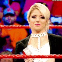 a woman is standing in a wrestling ring holding a microphone and a sign that says ' wwe ' on it